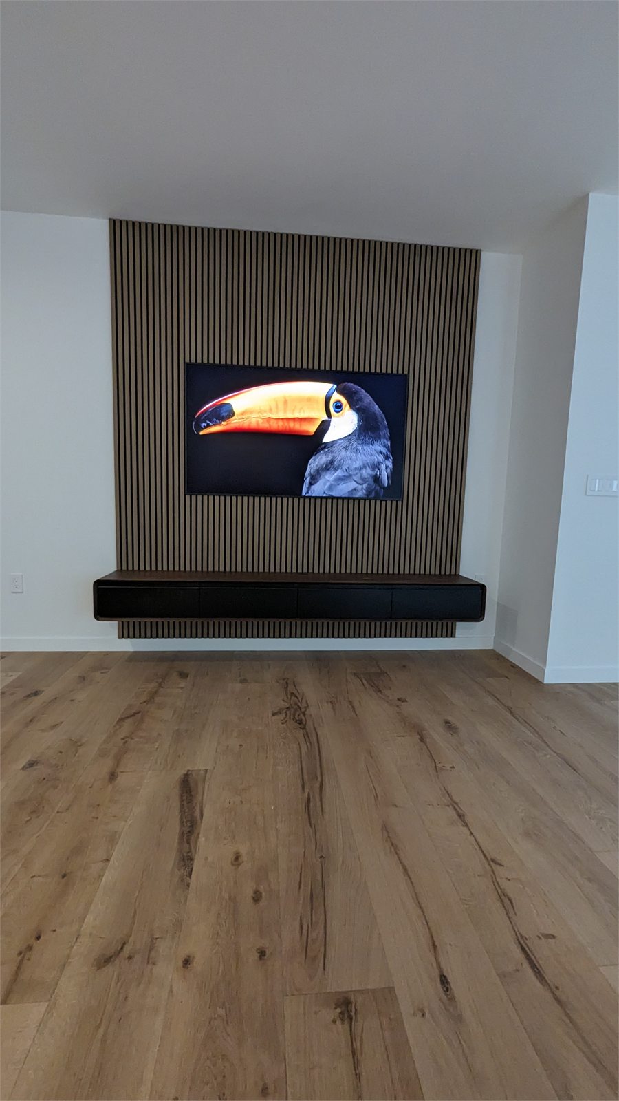 Custom wood slat media wall with floating storage console